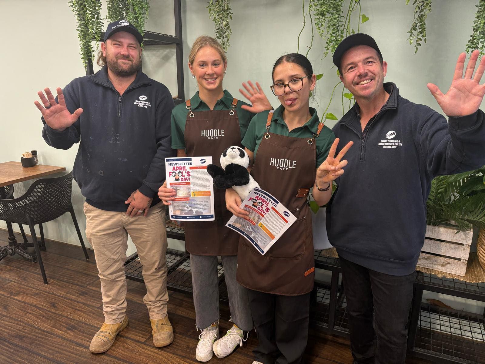 Four People in Aprons and Sweatshirts Wave — Expert Plumbing & Solar Services Bathurst in Kelso, NSW