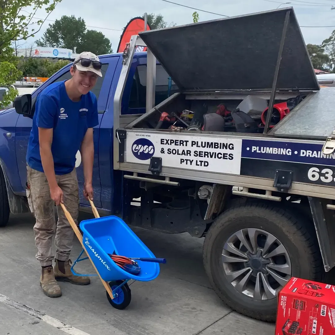 Man With a Wheelbarrow in Front of a Blue Plumbing Truck — Expert Plumbing & Solar Services Bathurst in Kelso, NSW