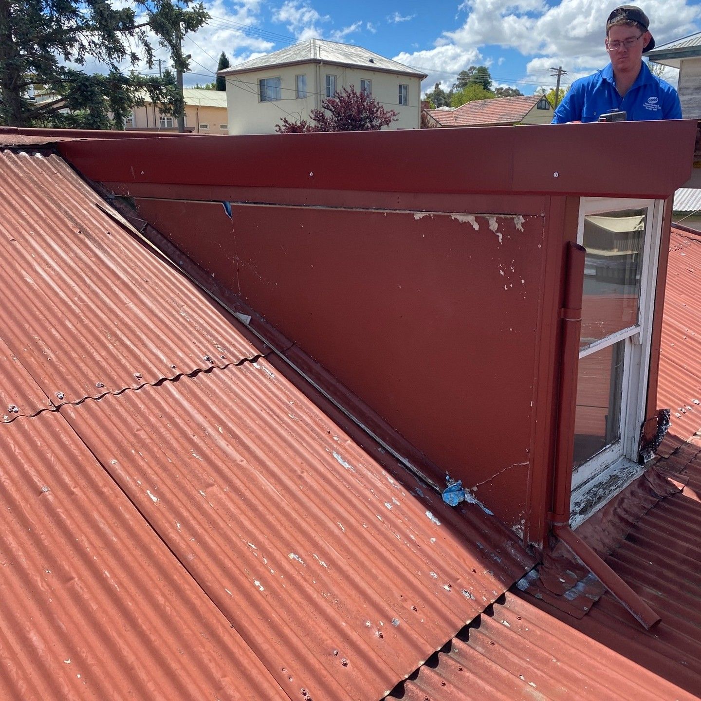 Red Corrugated Metal Roof With a Red Wall and Window — Expert Plumbing & Solar Services Bathurst in Lithgow, NSW