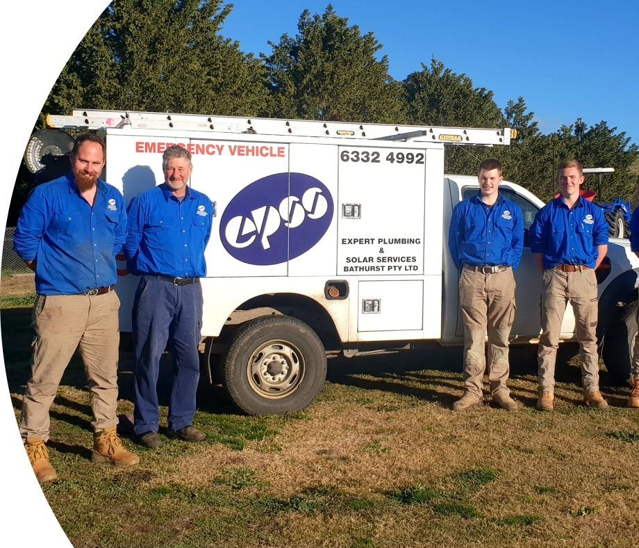 Four Men in Blue Shirts and Work Pants Stand — Expert Plumbing & Solar Services Bathurst in Kelso, NSW