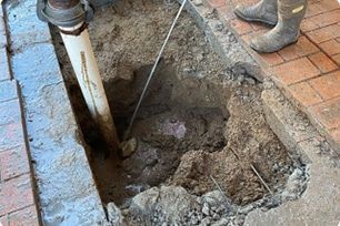 A Worker Stands Beside a Square Excavation Pit — Expert Plumbing & Solar Services Bathurst in Kelso, NSW