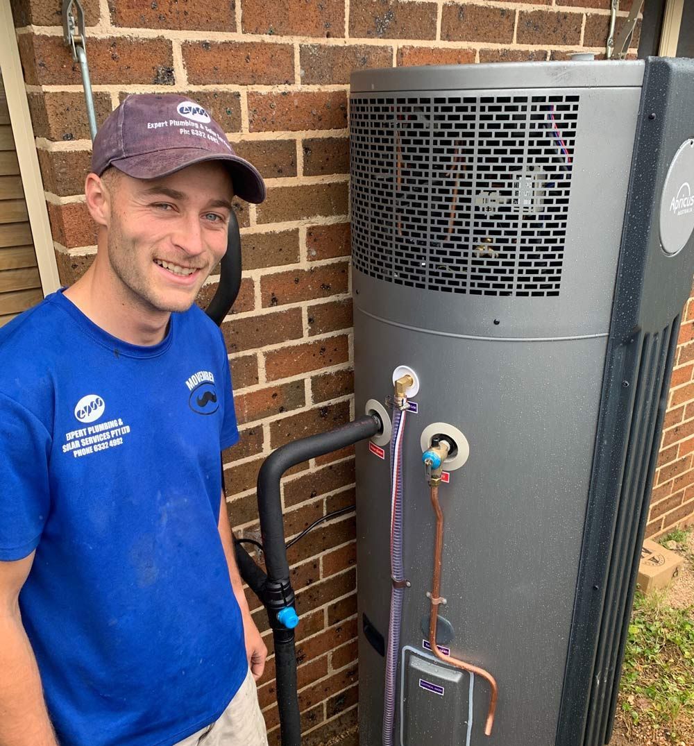 Man in Blue Shirt Smiles Next to a Large — Expert Plumbing & Solar Services Bathurst in Kelso, NSW