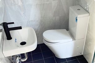 A Compact White Bathroom Set With a Corner Sink — Expert Plumbing & Solar Services Bathurst in Kelso, NSW