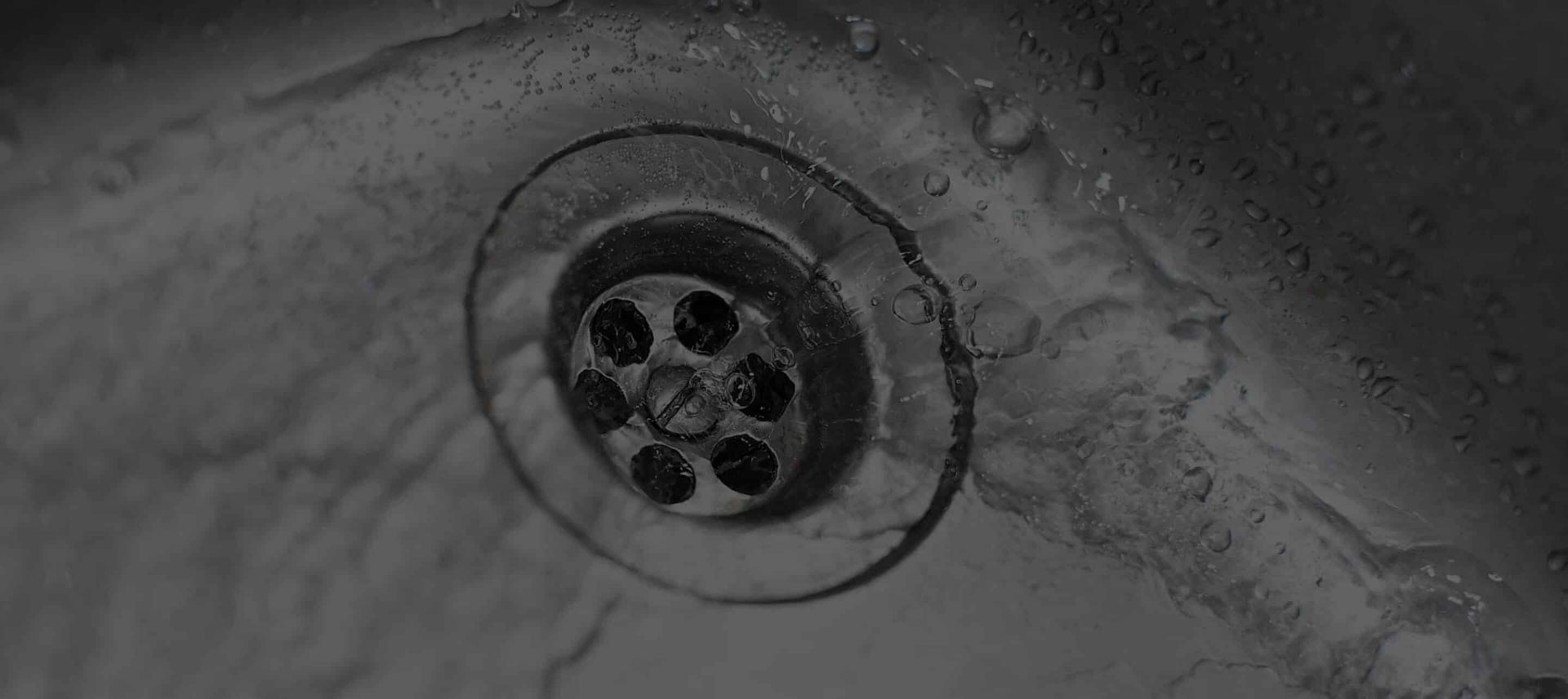 Close-up of a Sink Drain in a Stainless Steel Sink With Water Droplets — Expert Plumbing & Solar Services Bathurst in Kelso, NSW