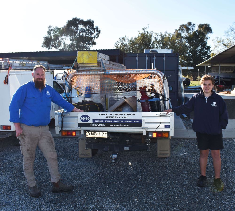 Two People Stand by a Work Truck Loaded With Equipment — Expert Plumbing & Solar Services Bathurst in Kelso, NSW