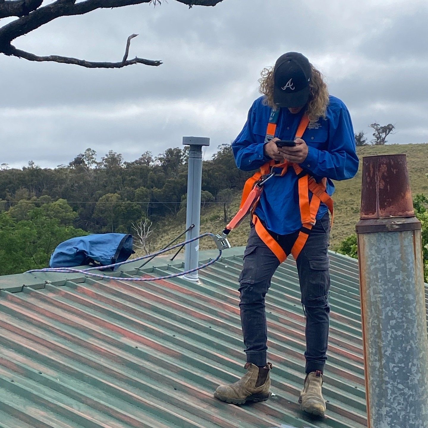 A Person Wearing Safety Gear on a Rooftop — Expert Plumbing & Solar Services Bathurst in Lithgow, NSW