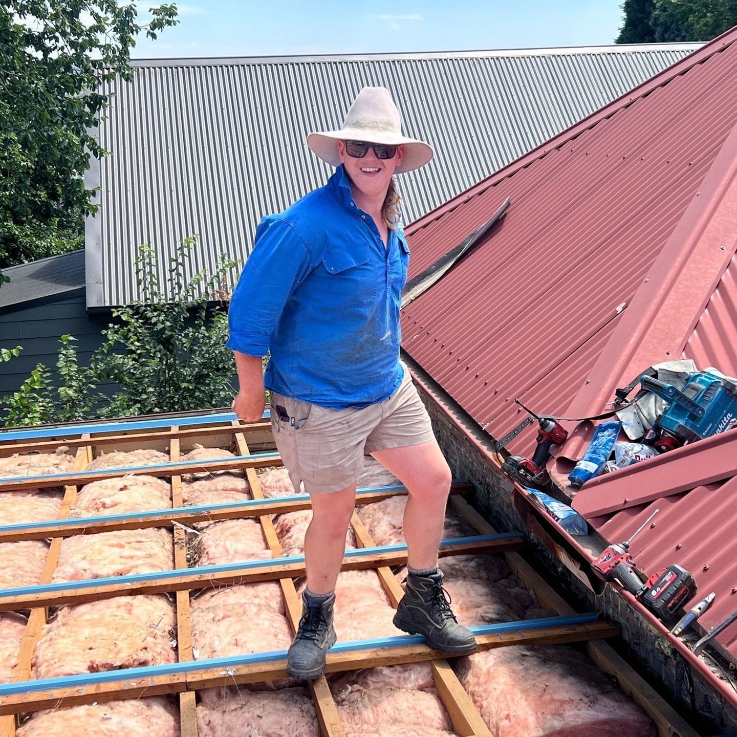 Person in Hat and Work Clothes Stands on a Roof — Expert Plumbing & Solar Services Bathurst in Kelso, NSW