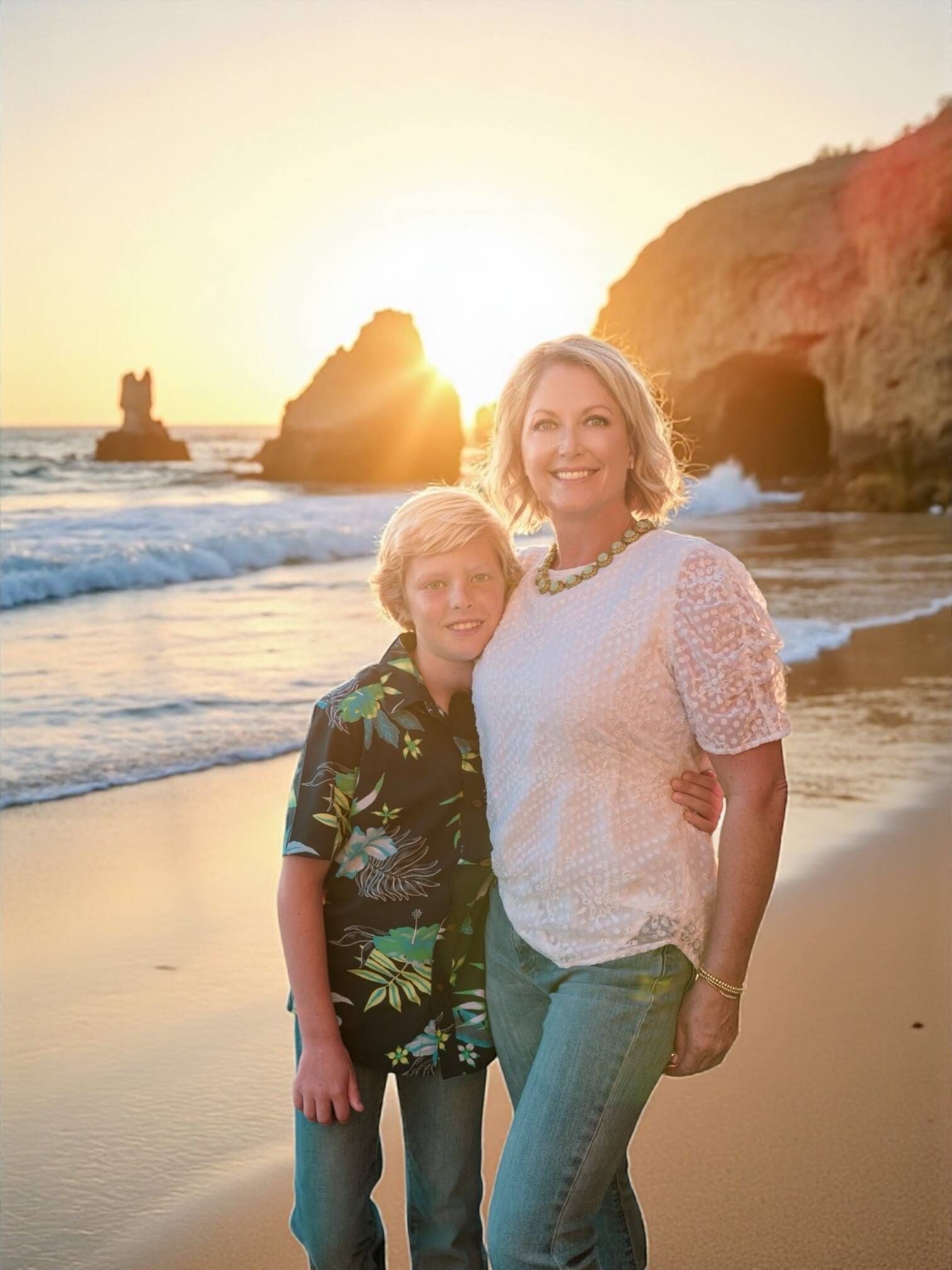 Woman and boy on a beach at sunset, Corona del Mar, CA sunlit water and cliffs behind them by Jelena's Photo.
