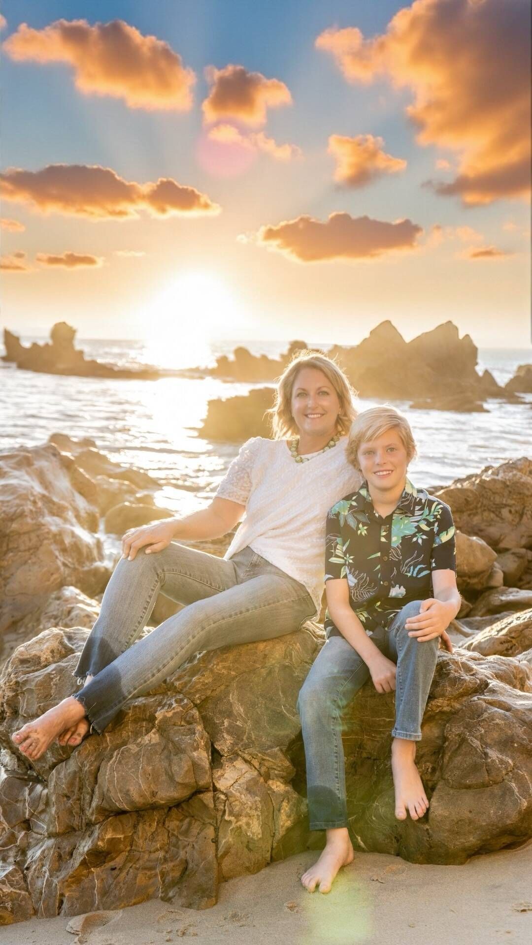 Woman and boy sitting on rocks at beach, sunset in background Jelena's Photo.
