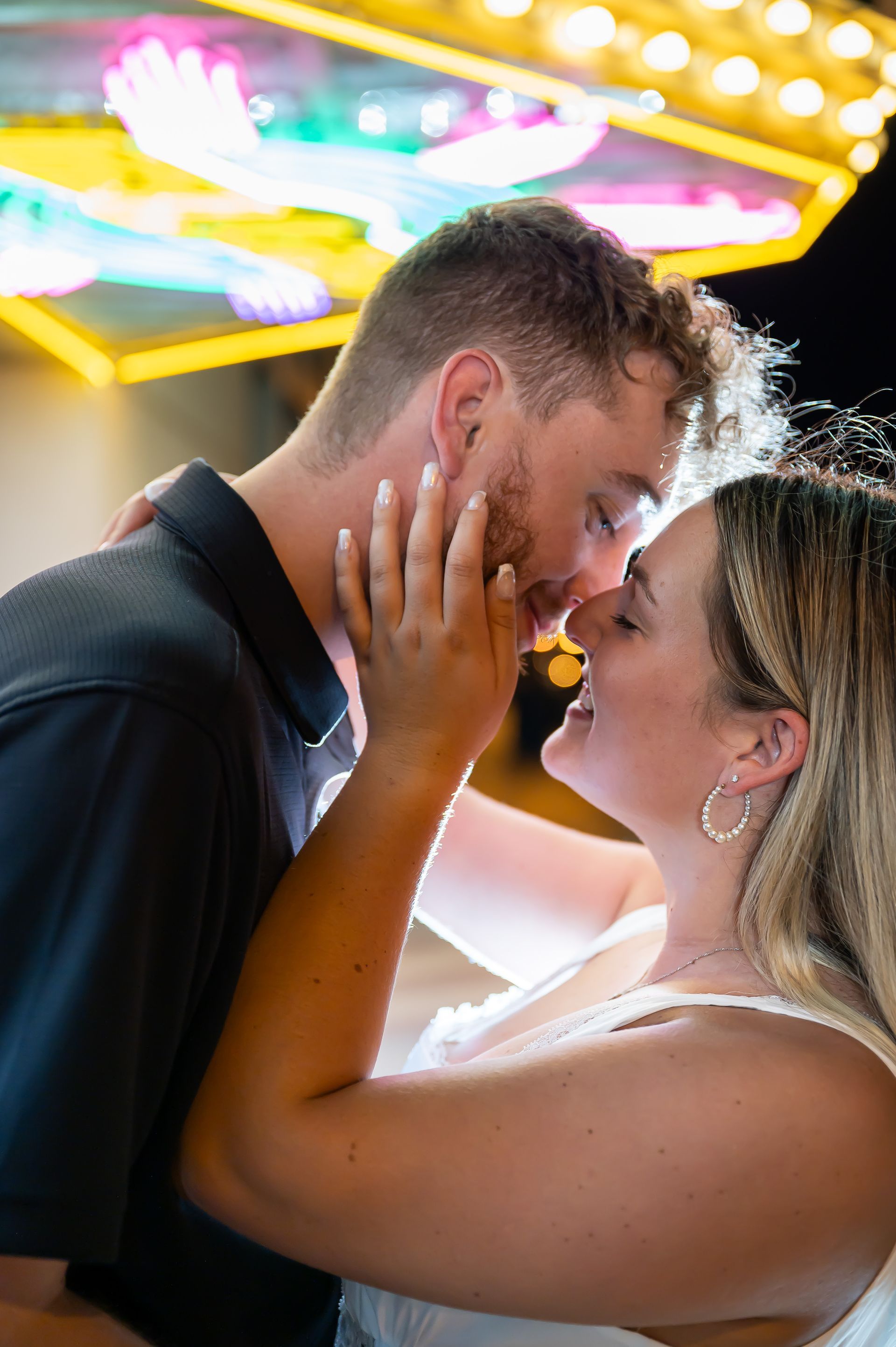 A man and a woman are kissing in front of a carnival ride.