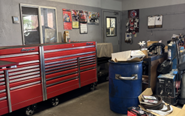 Red toolbox in a cluttered garage, with posters on the wall and a blue barrel in the center. | Autoplex Auto Service