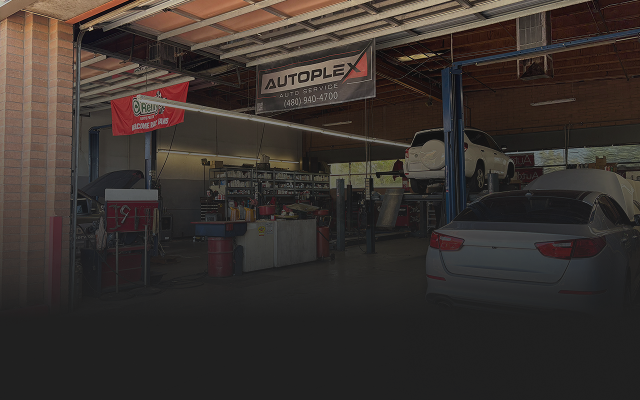 Auto repair shop interior with vehicles on lifts and open bay doors. | Autoplex Auto Service