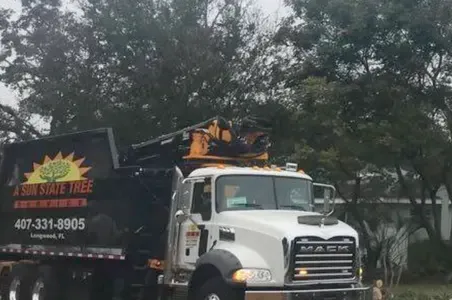 A mack truck is parked in front of a tree.