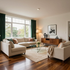 Bright living room with beige sectional, glass coffee table, wood floor, and large window with dark green curtains