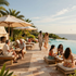Resort pool deck with loungers, umbrellas, and guests relaxing by an ocean-view infinity pool