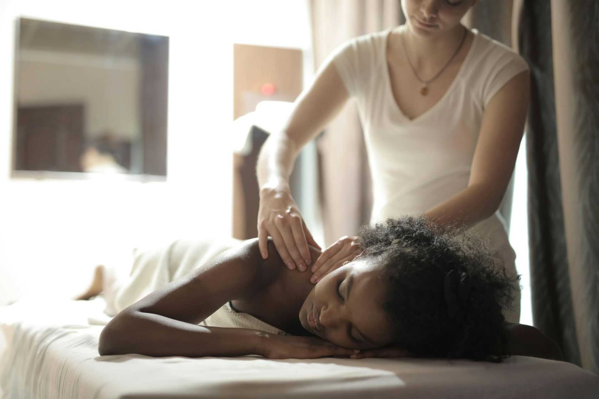 Person receiving a shoulder massage while resting on a table in a softly lit room