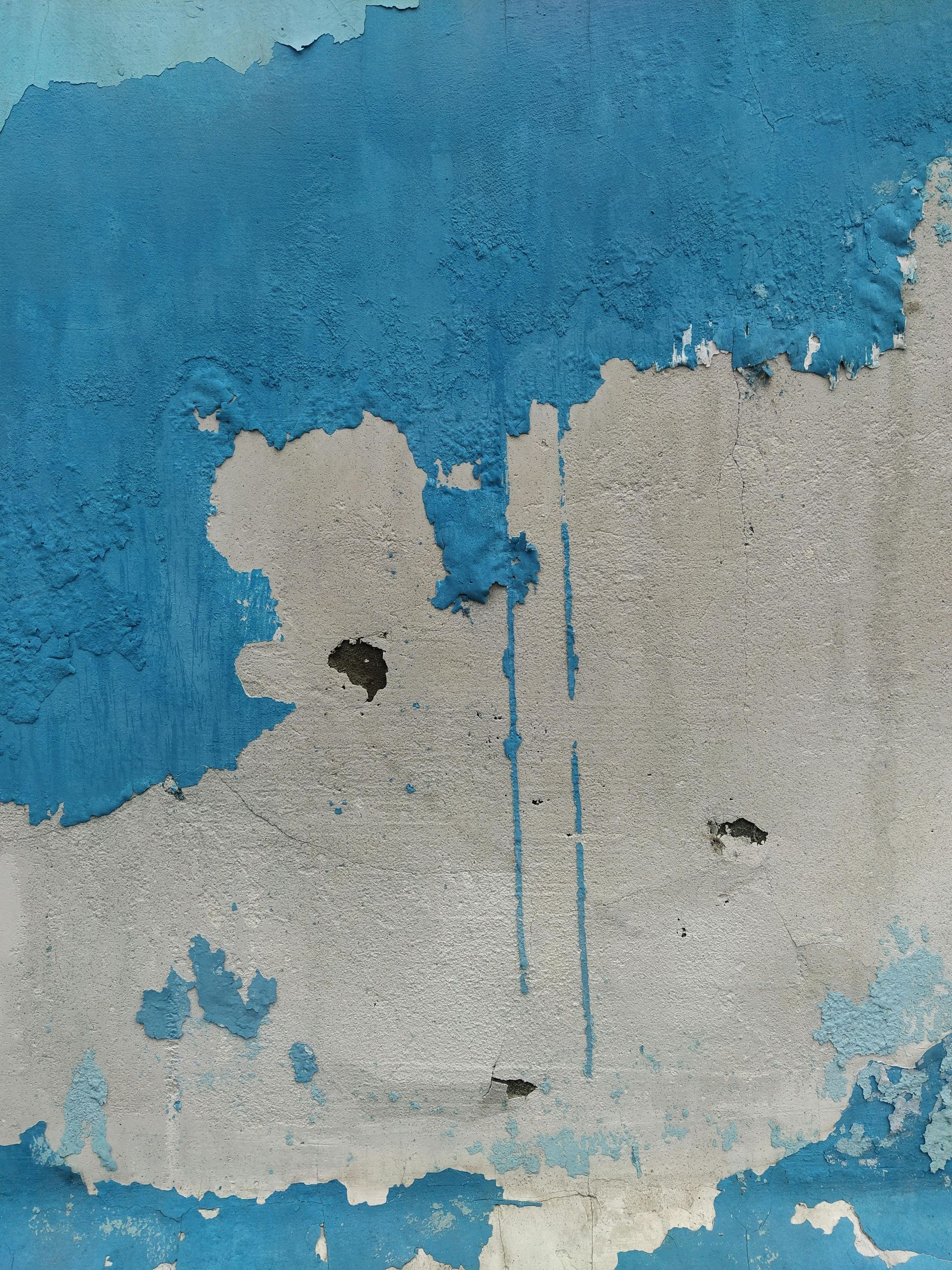 A close up of a blue and white wall with peeling paint