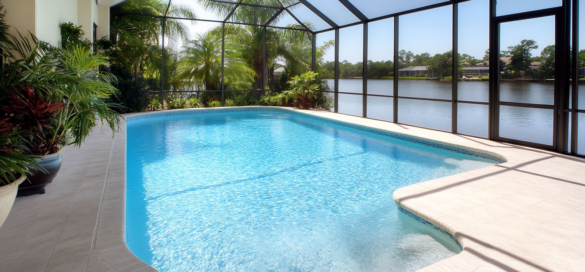 Pool with a view of water, screened patio, and greenery.