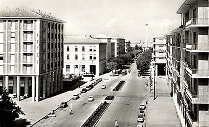 Una foto in bianco e nero di una strada cittadina con delle auto che la percorrono.