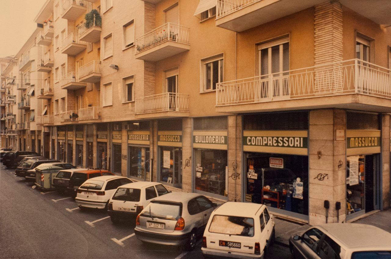 Una fila di auto è parcheggiata davanti a un edificio su cui è scritto