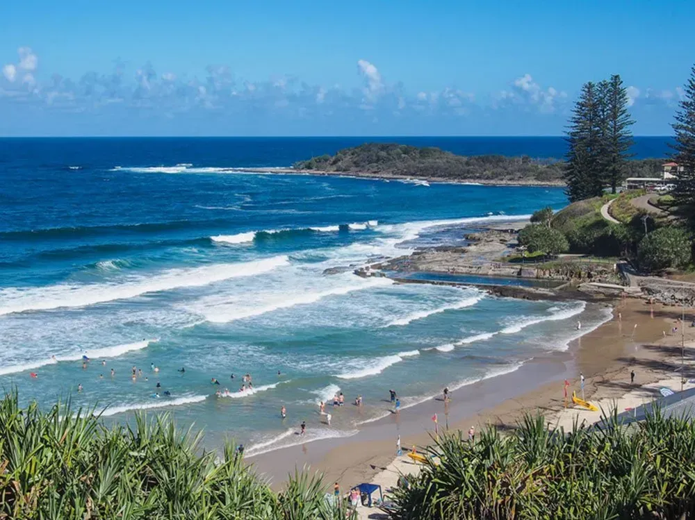 An Aerial View of a Beach Surrounded by Trees and Waves on a Sunny Day — O'Grady's Transport & Removals in Yamba, NSW