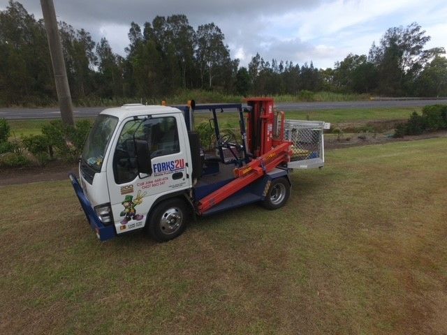 A Tow Truck With a Crane Attached to the Back is Parked in a Grassy Field — O'Grady's Transport & Removals in Ballina, NSW