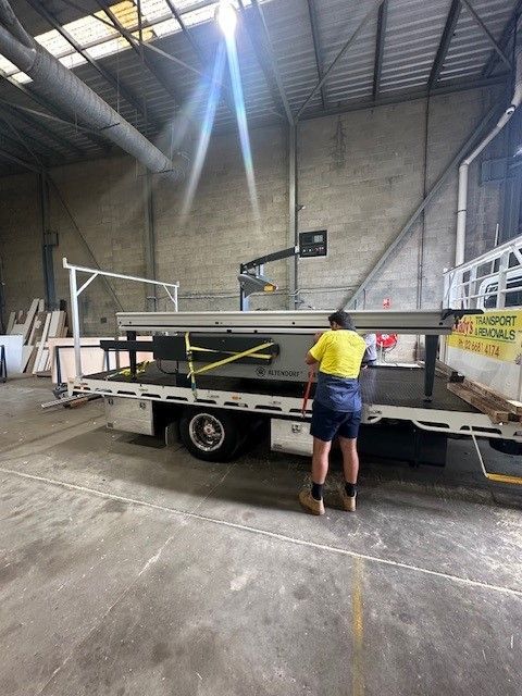A Man is Standing Next to a Tow Truck in a Warehouse — O'Grady's Transport & Removals in Alstonville, NSW