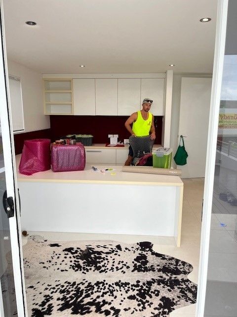 A Man in a Yellow Tank Top is Standing in a Kitchen — O'Grady's Transport & Removals in Brisbane, NSW
