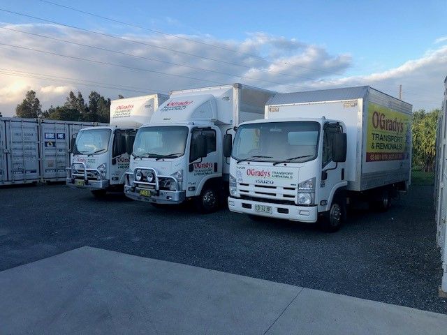 A Row of Moving Trucks Are Parked in a Parking Lot — O'Grady's Transport & Removals in Gosford, NSW