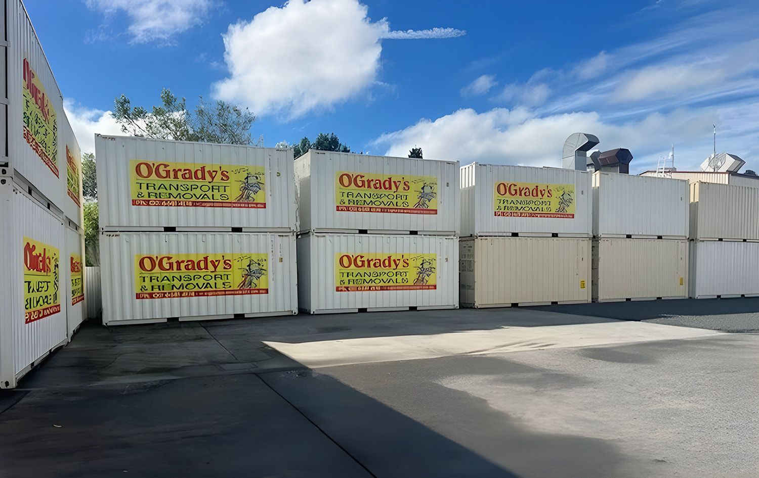 Stacked White Shipping Containers With O'Grady's Transport Branding Sit