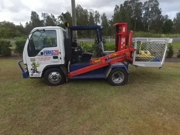 A Truck With a Crane Attached to It is Parked in a Grassy Field — O'Grady's Transport & Removals in Alstonville, NSW