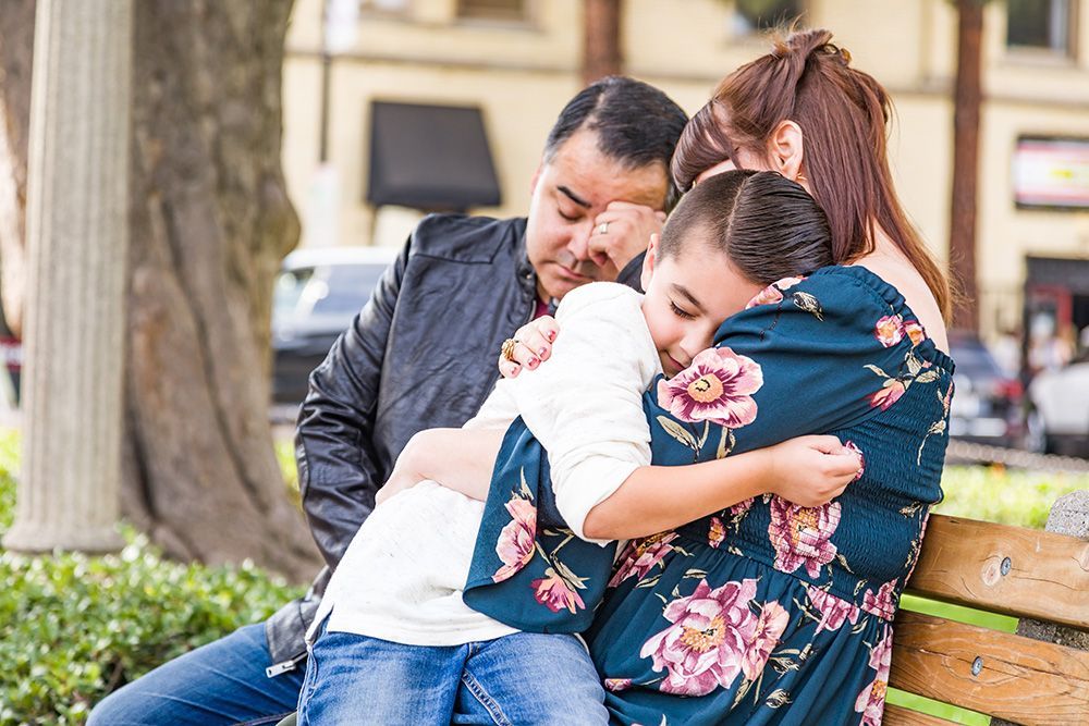 family together on bench embracing each other during difficult time