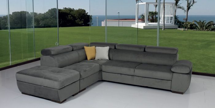 Un divano componibile grigio è posizionato di fronte a una parete di vetro.