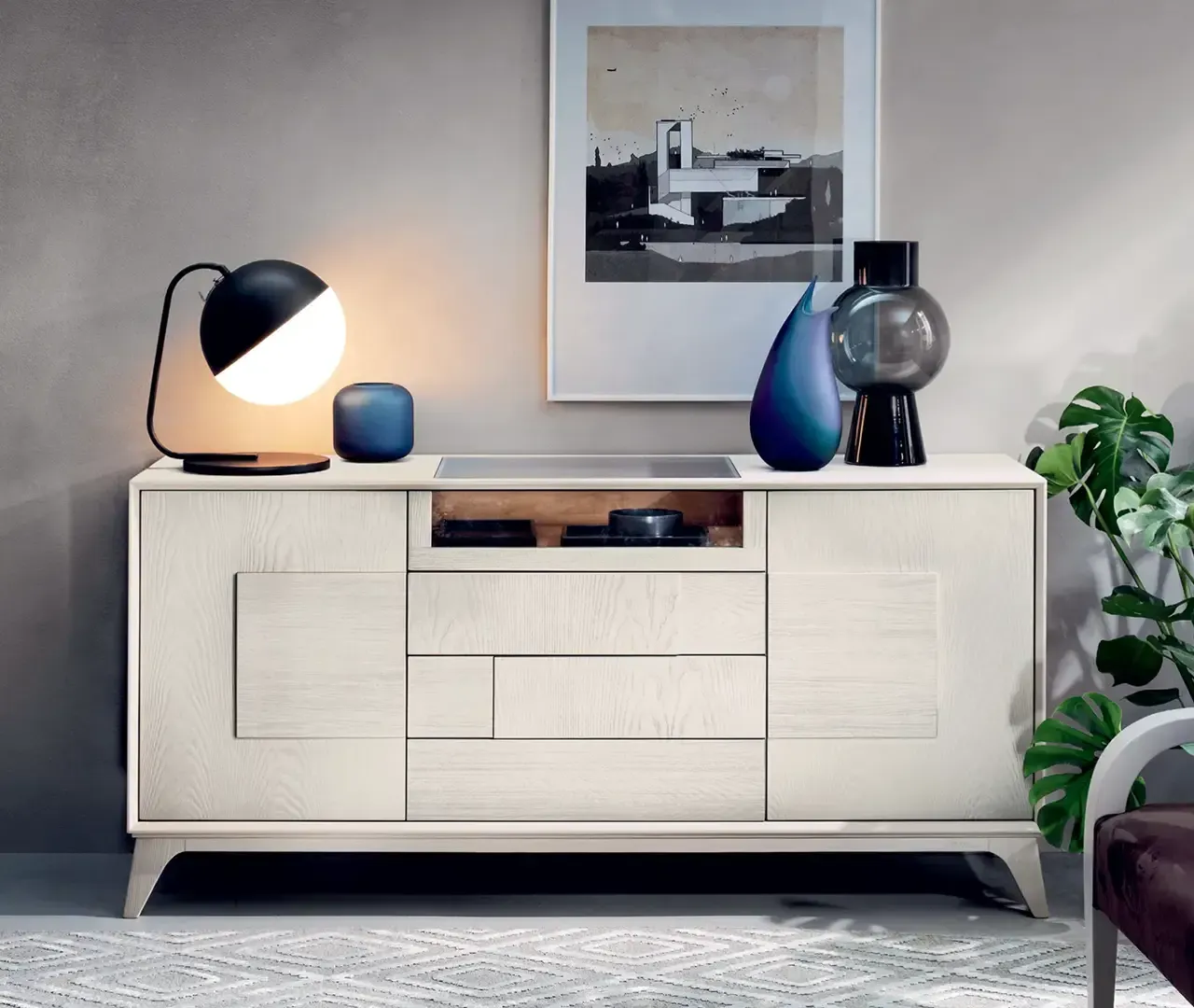 Una cassettiera bianca con una lampada e dei vasi sopra