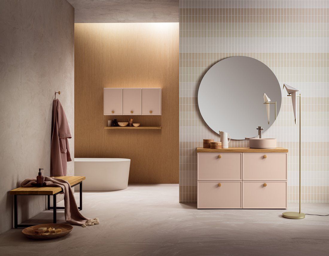 Un bagno con mobili rosa, un lavandino, uno specchio e una vasca da bagno.