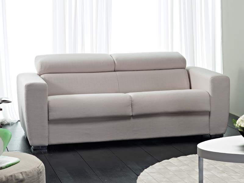 Un divano bianco è posizionato nel soggiorno, accanto a una finestra.