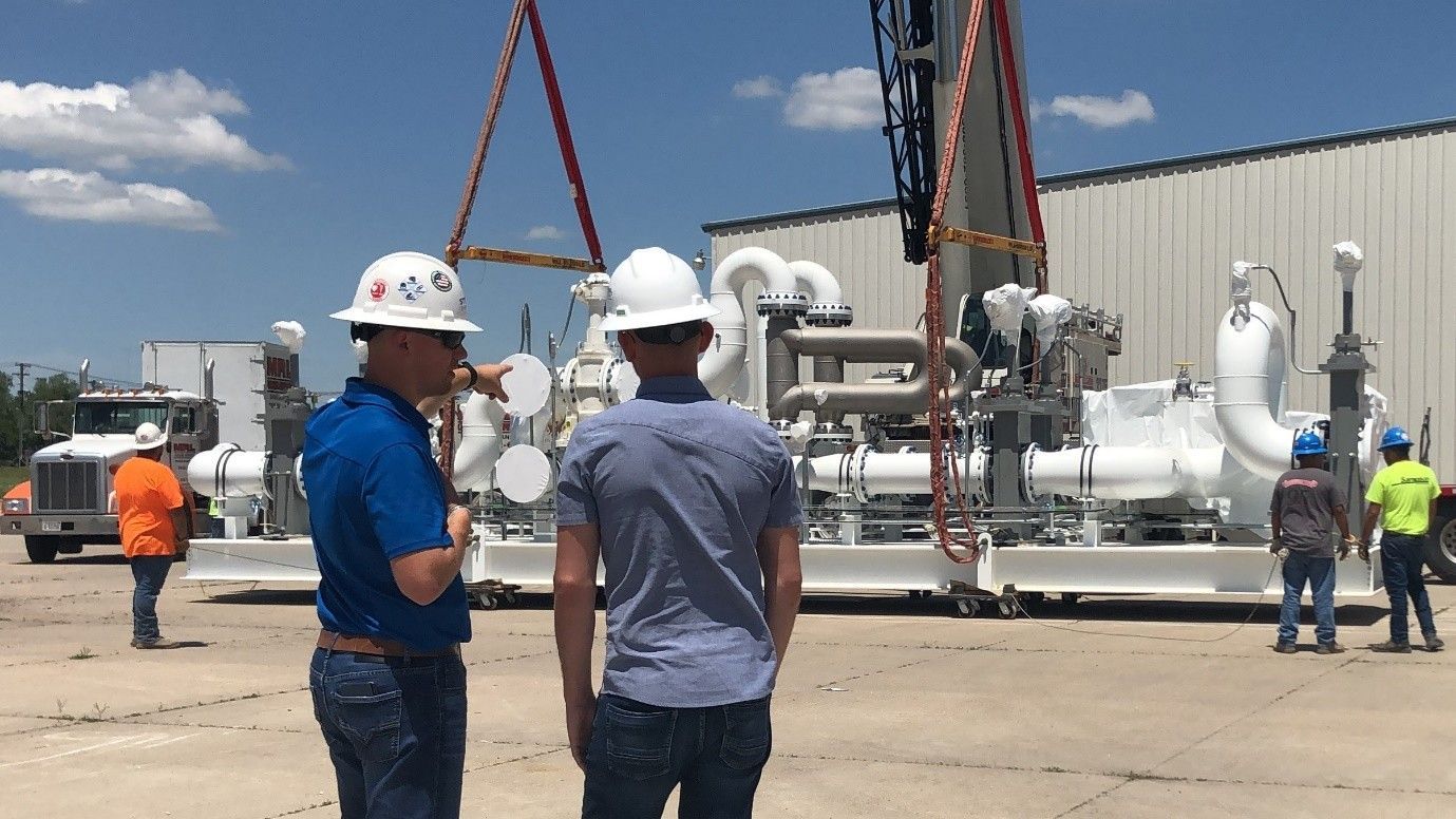 Four professionals standing and talking. Two of the professionals are wearing hard hats.