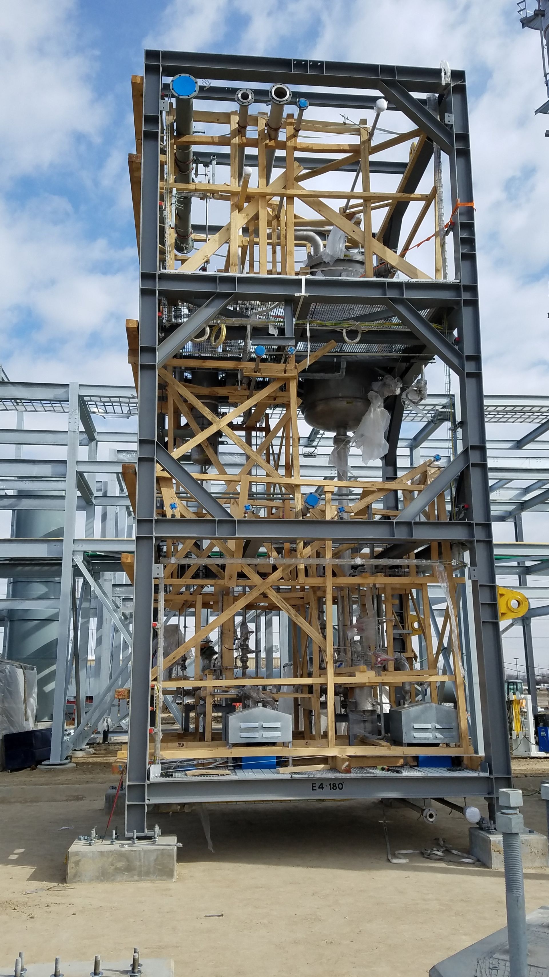 A large metal structure is being built on top of a dirt field.
