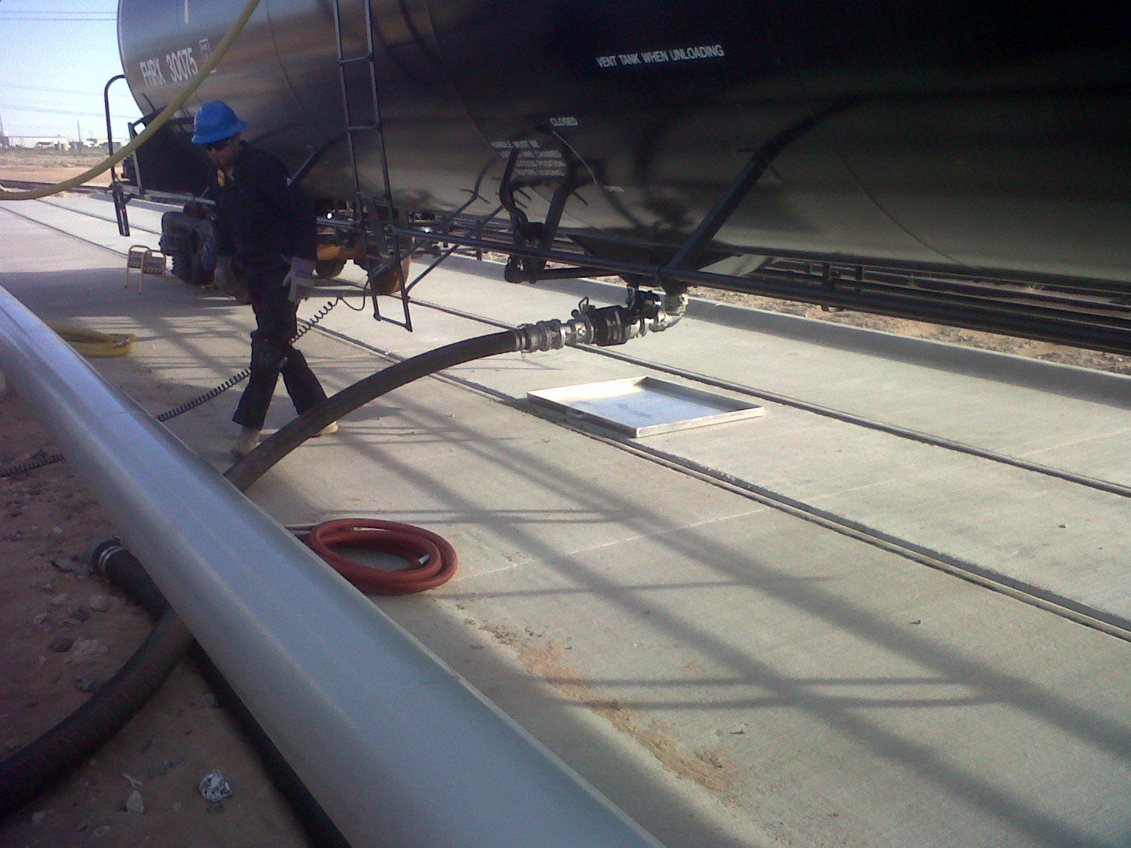A man in a blue hard hat is standing next to a train car