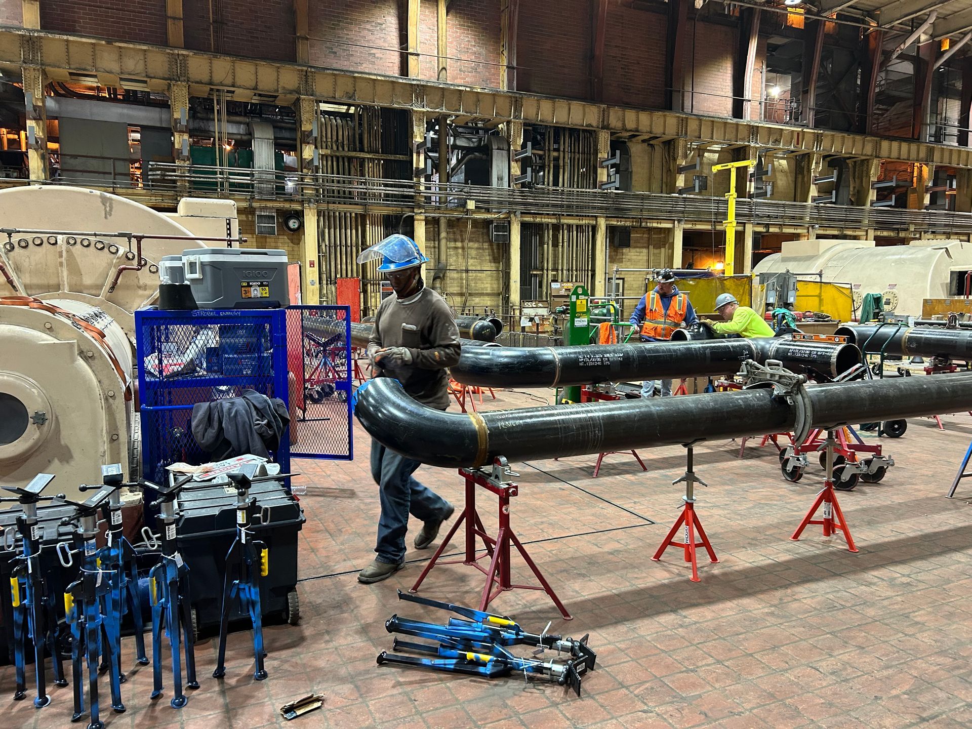 A man is working on a large pipe in a factory.