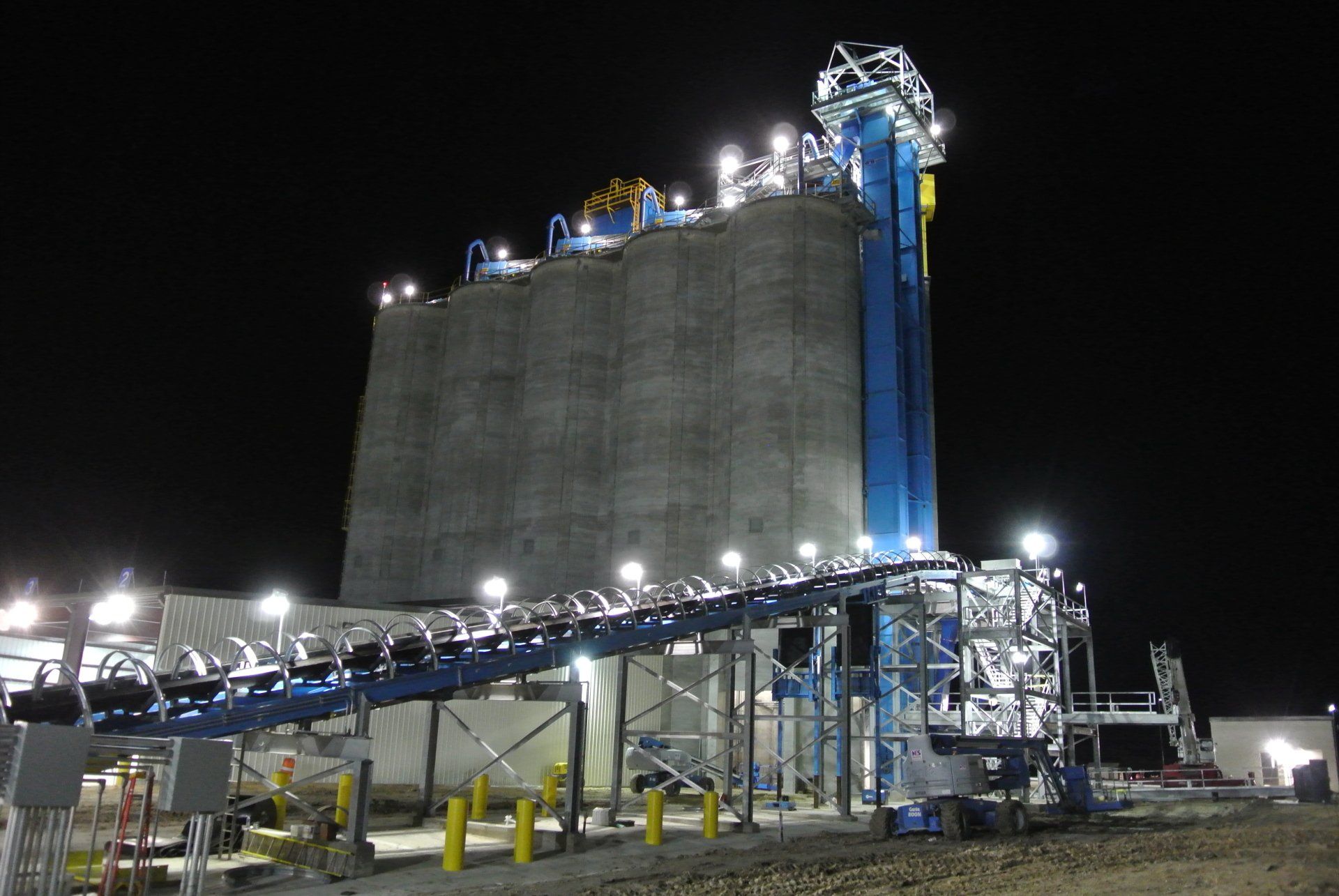 A large building with a conveyor belt in front of it at night.