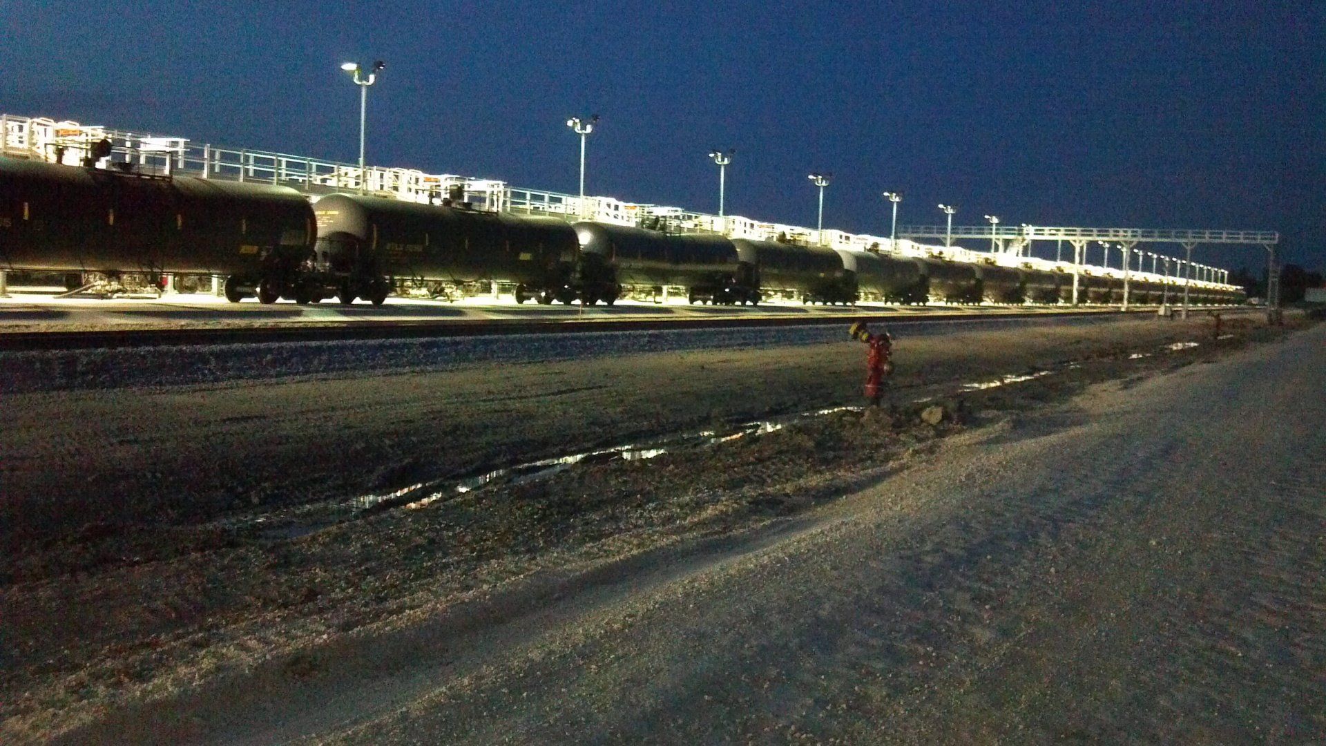 A row of train cars are parked on the tracks at night