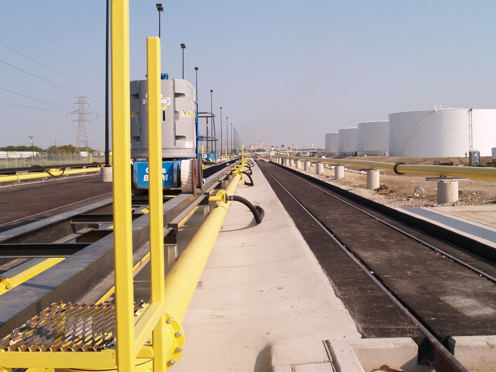 A yellow railing on the side of a train track