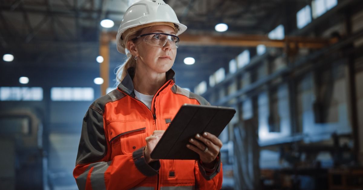 An engineer wearing a hard hat and safety goggles in an industrial facility.