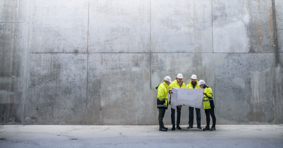 Four members of a construction crew looking at a large blueprint.