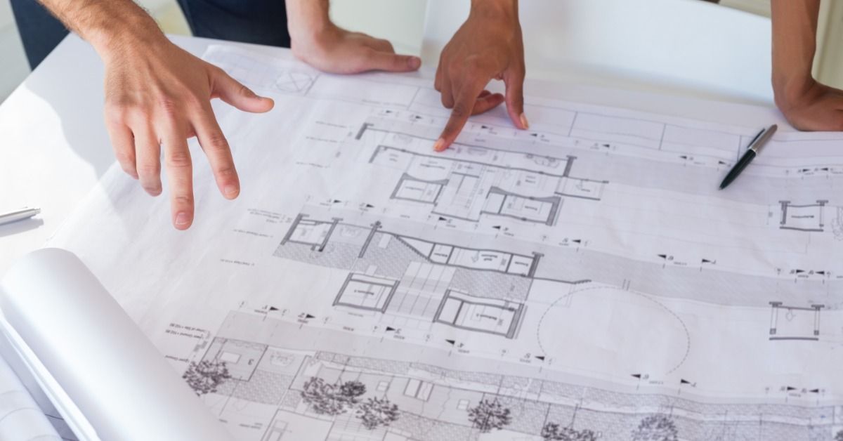 Two people looking at a set of blueprints for a construction project.