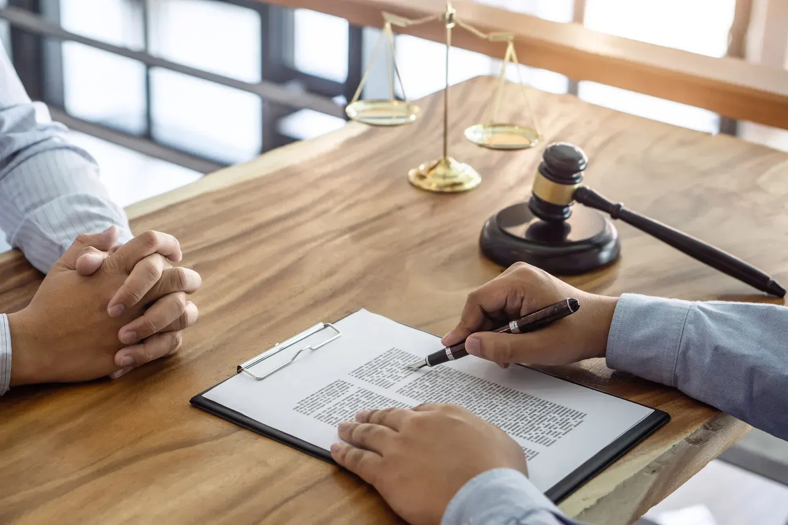 A lawyer is sitting at a table with a client and signing a document.