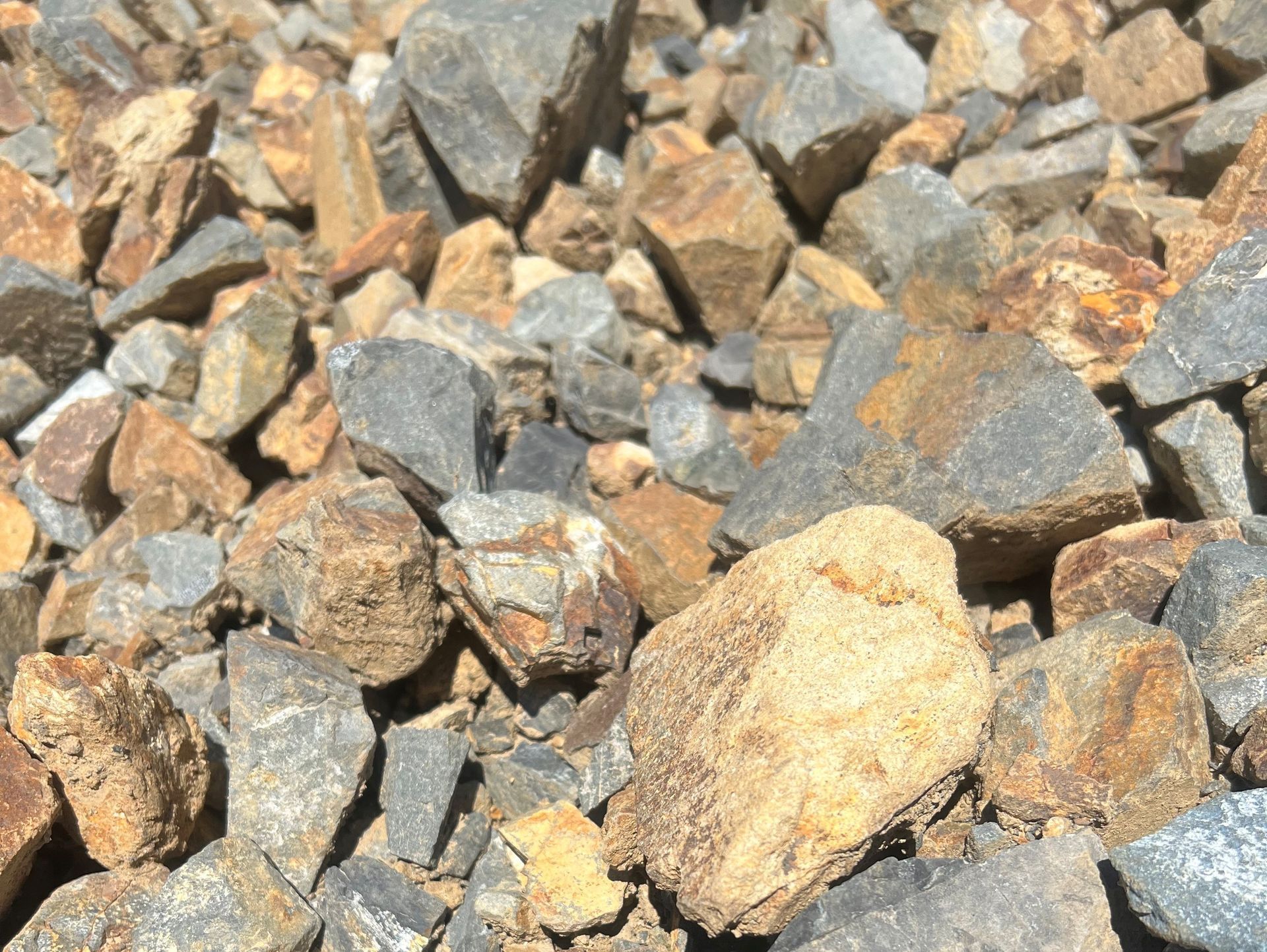 Pile of rough rocks in shades of gray, brown, and gold.