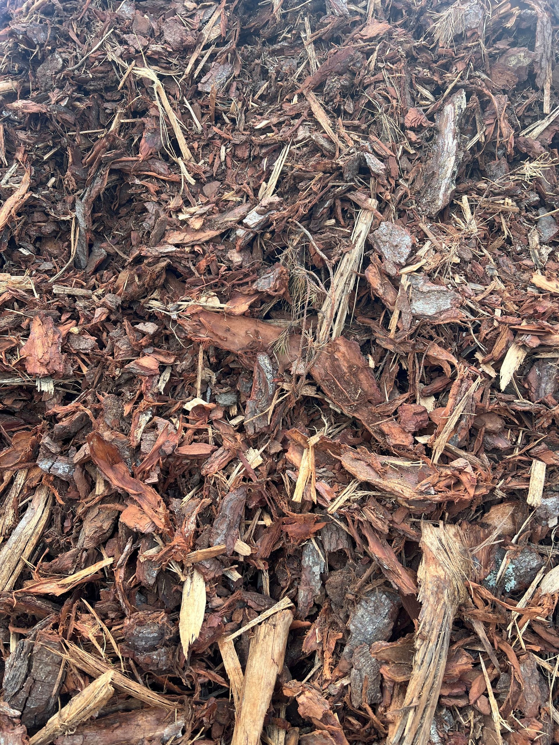 Brown wood chip mulch, textured, covering a surface.