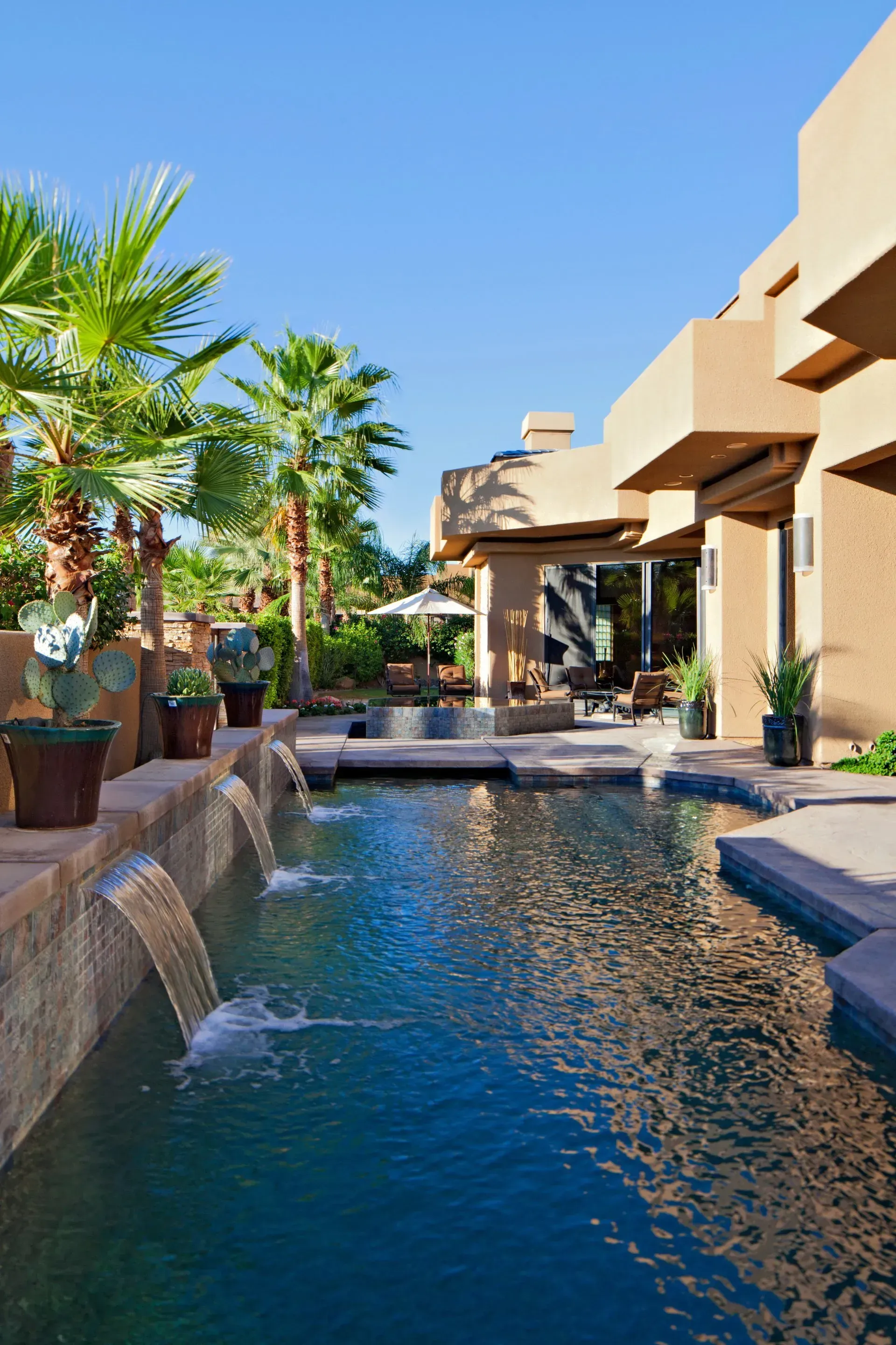 a large swimming pool with a waterfall in front of a house